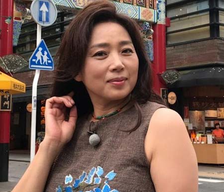 ノースリーブのトップスを着て街中にいる藤吉久美子の画像